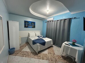 Un dormitorio con cama, una mesita de noche con un florero, un cuadro en la pared y una lámpara en el techo.