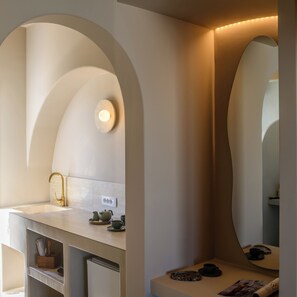 Ein modernes Badezimmer mit einem freistehenden Waschbecken, einem Goldarmaturen und einem Spiegel mit Beleuchtung darüber.