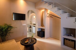 Ein modernes Interieur mit Fernseher, einem runden Tisch mit Snacks, einer Treppe und einer Pflanze.