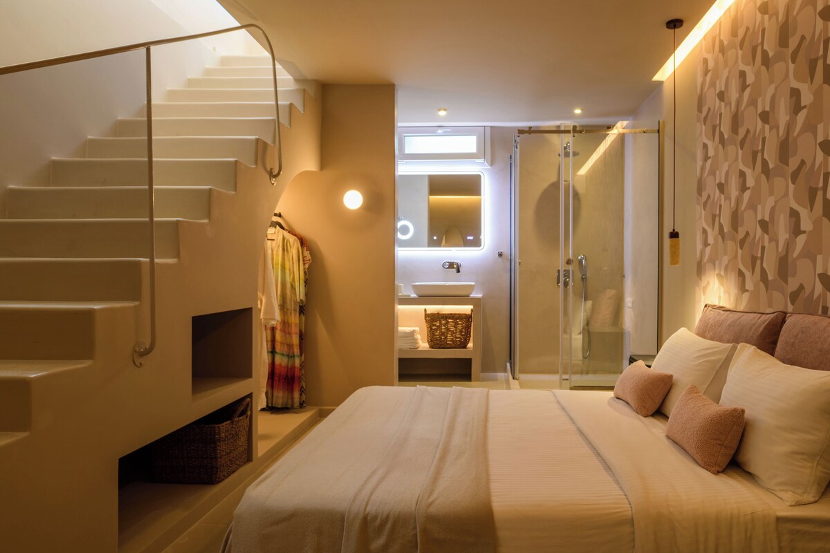A bedroom with a bed, a bathroom with a shower, and a staircase.