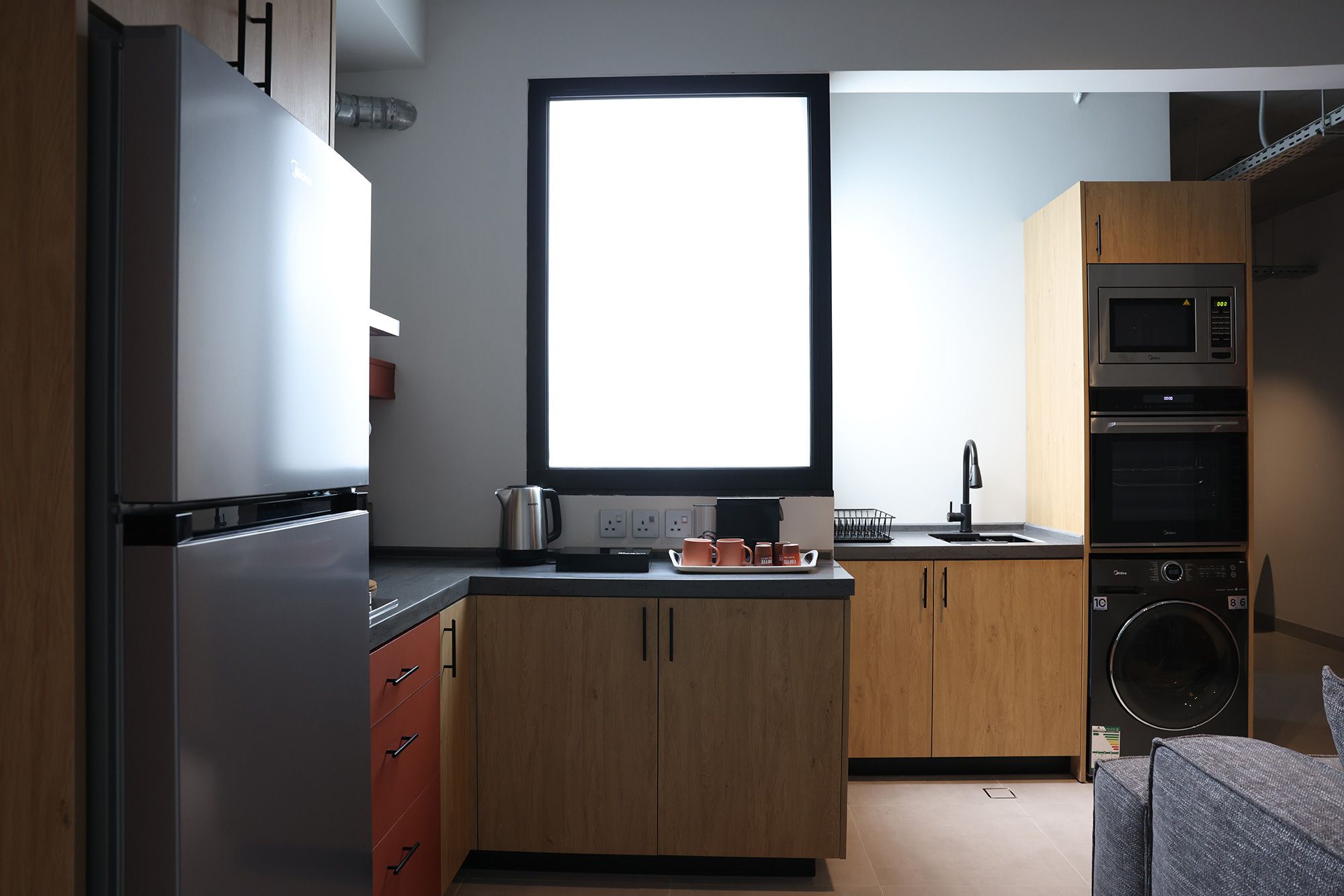 A modern kitchen with a refrigerator, oven, microwave, and sink.
