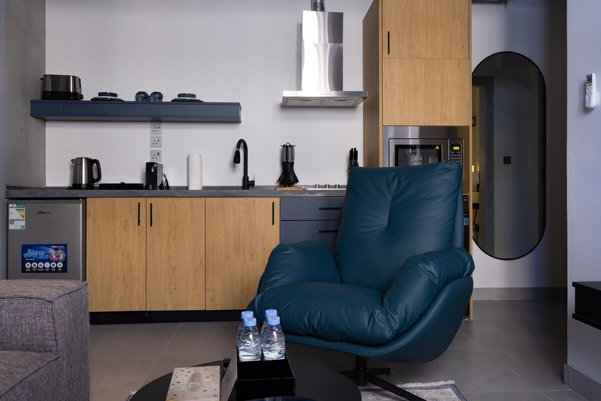 A modern kitchen with a built-in microwave, a coffee maker, and a kettle on the counter.