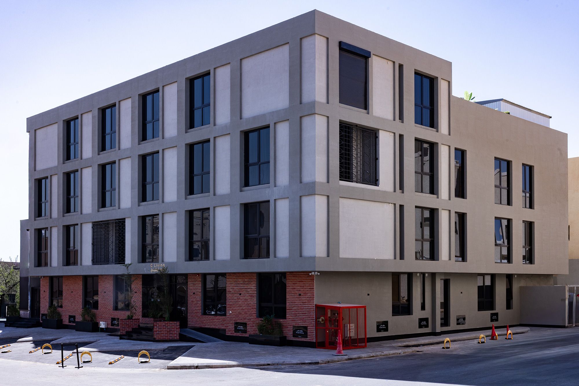 Un edificio moderno con fachada plana, múltiples ventanas y base de ladrillo.