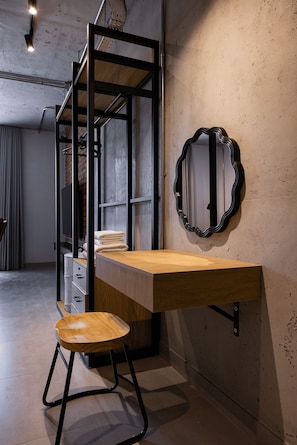 A modern room with a wooden desk, a stool, a mirror, and a metal shelving unit. - C Living 3 (Madinat Zayed)