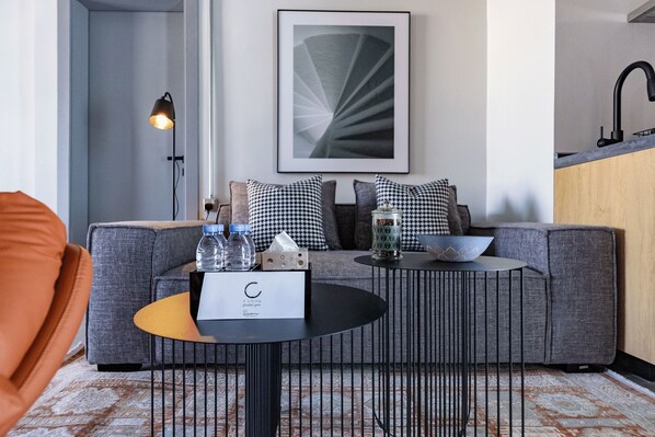 A modern living room with a grey sofa, a black coffee table, and a framed abstract artwork on the wall. - C Living 3 (Madinat Zayed)