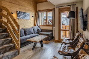 Ein Holzinnenraum mit einer Couch, einem Couchtisch und einer Hängematte.