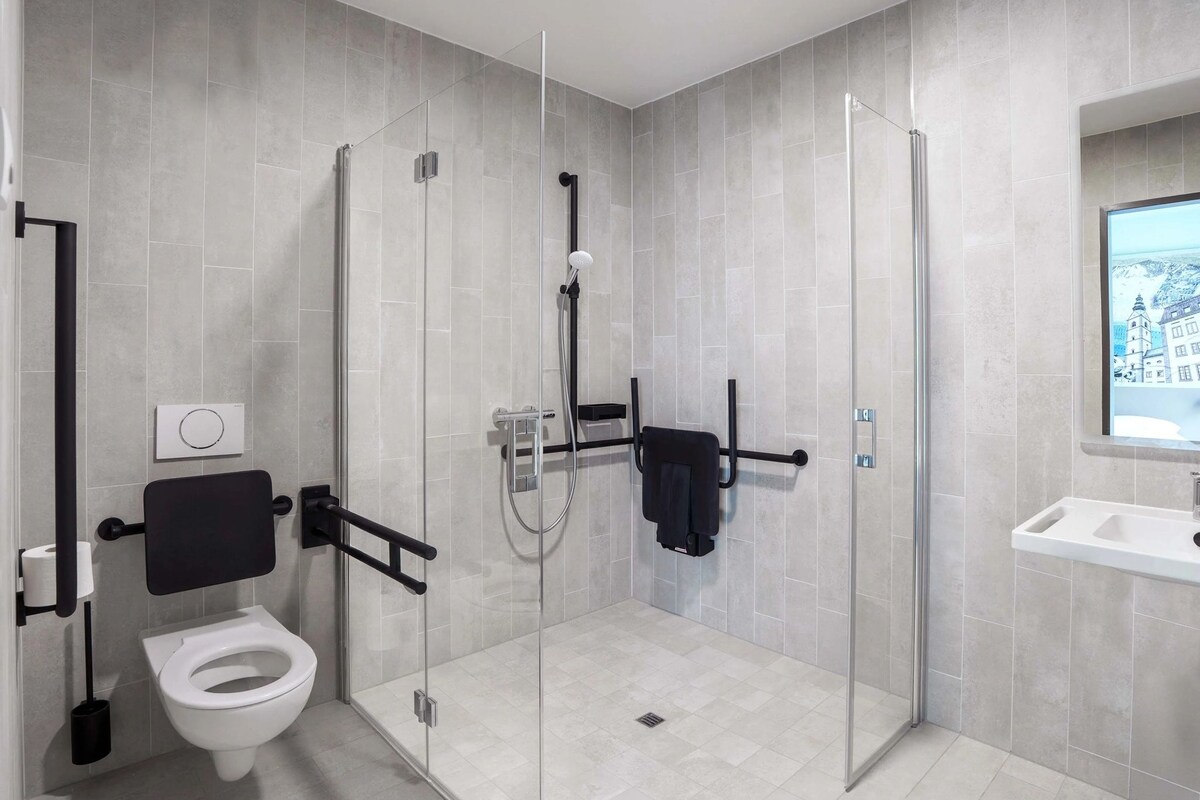 Ein modernes Badezimmer mit einer gläsernen Duschkabine, einer Toilette und einem Waschbecken.
