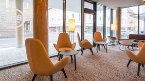 A modern hotel lobby with large windows, seating areas, and a visible street view. - B&B Hotel Klagenfurt-city (Sankt Veit an der Glan)