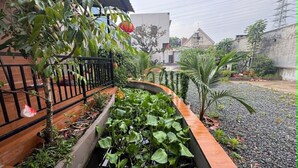 Ein Garten mit einer Holzdielen-Terrasse, einem erhöhten Blumenbeet mit Grünpflanzen und einem Kiesbereich.
