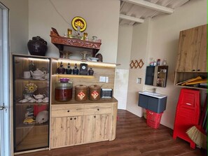 A kitchen with wooden cabinets, a refrigerator, a sink, and a wooden cabinet with decorative items.