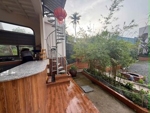 A kitchen with a curved countertop, a spiral staircase, and a small outdoor garden area with plants and a red lantern.
