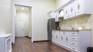 A kitchen with white cabinetry, a refrigerator, and a tiled backsplash. - Antique Palace Hotel Baku (Baku)