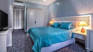 A bedroom with a bed, a television, a nightstand, and a patterned carpet. - Antique Palace Hotel Baku (Baku)
