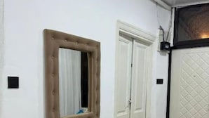 A room with a mirror, a bench, a door, and a tiled floor. - Antique Palace Hotel Baku (Baku)