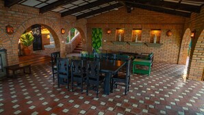 Una habitación con paredes de ladrillo, piso de baldosas, una mesa con sillas y una escalera.