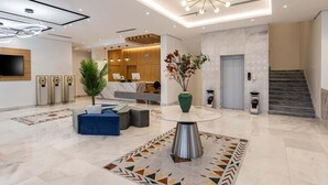 A modern hotel lobby with a reception desk, seating area, and a staircase. - Al Qasr Al Rabwah (Abha)