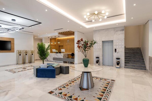 A modern hotel lobby with a reception desk, seating area, and a staircase. - Al Qasr Al Rabwah (Abha)