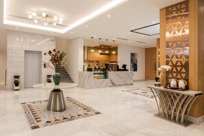 A modern hotel lobby with a reception desk, marble flooring, and contemporary lighting fixtures. - Al Qasr Al Rabwah (Abha)