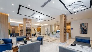 A spacious lobby with modern furniture, a reception desk, and a kitchen area in the background. - Al Qasr Al Rabwah (Abha)