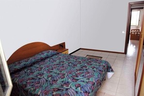 A bedroom with a bed, a nightstand, and a mirror.