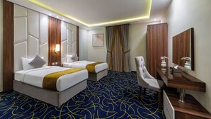 Quarto de hotel com duas camas, uma escrivaninha, uma cadeira e um espelho grande.