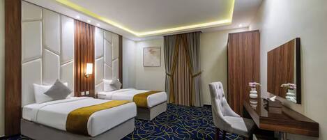 Habitación de hotel con dos camas, un escritorio, una silla y un espejo grande.