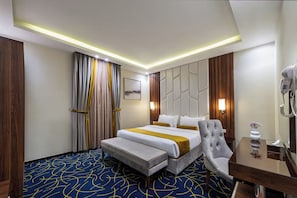 A hotel room with a bed, a chair, a desk, and a mirror.
