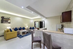 A modern living room with a sofa, coffee table, and a dining area.