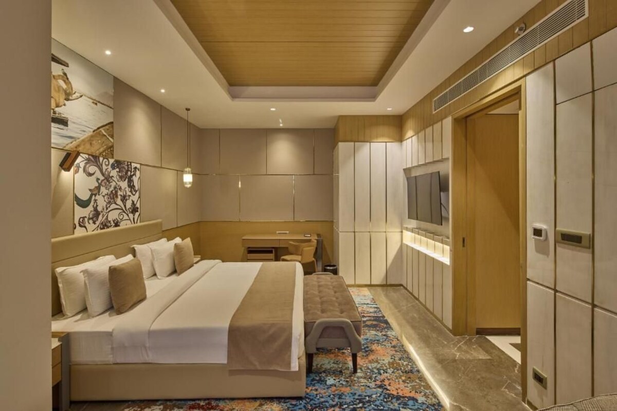 Habitació d'hotel amb un llit, escriptori, televisió i armari.