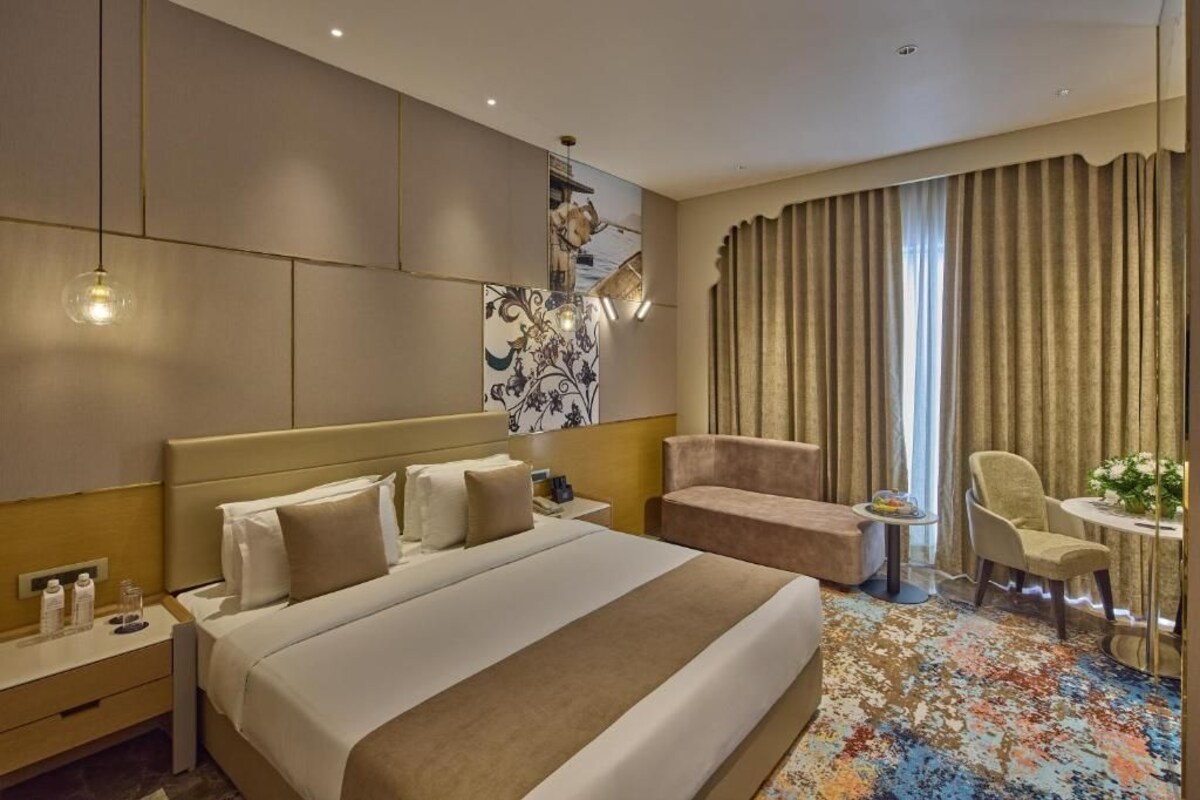 Una habitació d'hotel amb un llit gran, un sofà, una taula petita i una cadira.