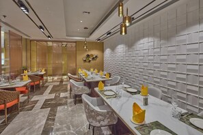 A modern dining area with marble flooring, multiple dining tables, and chairs. - Grand Continent Luxury Collection, Udaipur (Udaipur)