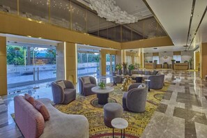 A spacious lobby with modern furniture, a patterned carpet, and a glass entrance leading outside. - Grand Continent Luxury Collection, Udaipur (Udaipur)