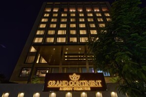 Edifici d'hotel de diversos pisos amb finestres il·luminades i un rètol que diu 'Grand Continental A Luxury Collection'.