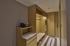 Habitació d'hotel senzilla amb escriptori integrat, un armari i una petita zona de seients.