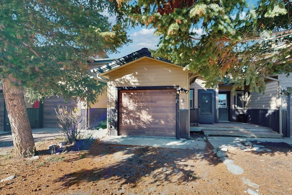 Une maison de plain-pied avec un garage, une véranda et un jardin bien entretenu.
