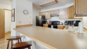 A kitchen with wooden cabinets, a refrigerator, a stove, and a sink. - Stylish townhouse with WiFi, private washer/dryer, patio, and full kitchen (Big Sky)