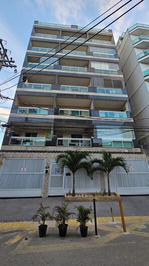 Un immeuble à plusieurs étages doté de balcons, d’une entrée sécurisée et de plantes en pot.