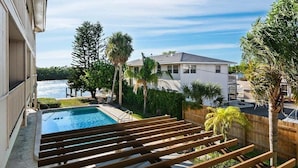 Ein Wohnhaus mit Swimmingpool, Holzterrasse und Blick auf ein Gewässer.