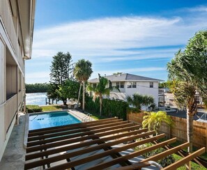 Ein Wohnhaus mit Swimmingpool, Holzterrasse und Blick auf ein Gewässer.