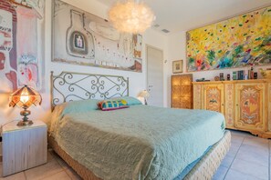 A bedroom with a bed, a nightstand, a lamp, a decorative cabinet, and artwork on the walls. - Panoramic villa overlooking the Gulf of Portoferraio (Portoferraio)