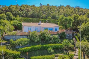 A two-story house with a tiled roof, surrounded by lush greenery and a stone wall. - Panoramic villa overlooking the Gulf of Portoferraio (Portoferraio)
