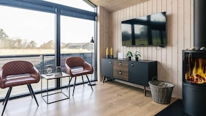 Un salon moderne avec une cheminée, un téléviseur et un balcon offrant une vue agréable.