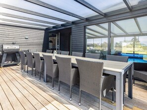 An outdoor deck with a grill, dining table, and chairs. - 5 Star Holiday Home in Hjorring (Hjørring)