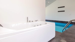 Une salle de bain moderne avec une grande baignoire blanche, un espace douche séparé et une piscine.