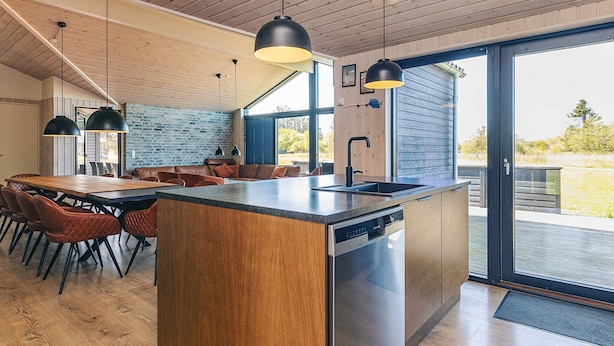 Une cuisine moderne dotée d’un îlot central, d’un plafond en bois et de grandes fenêtres.