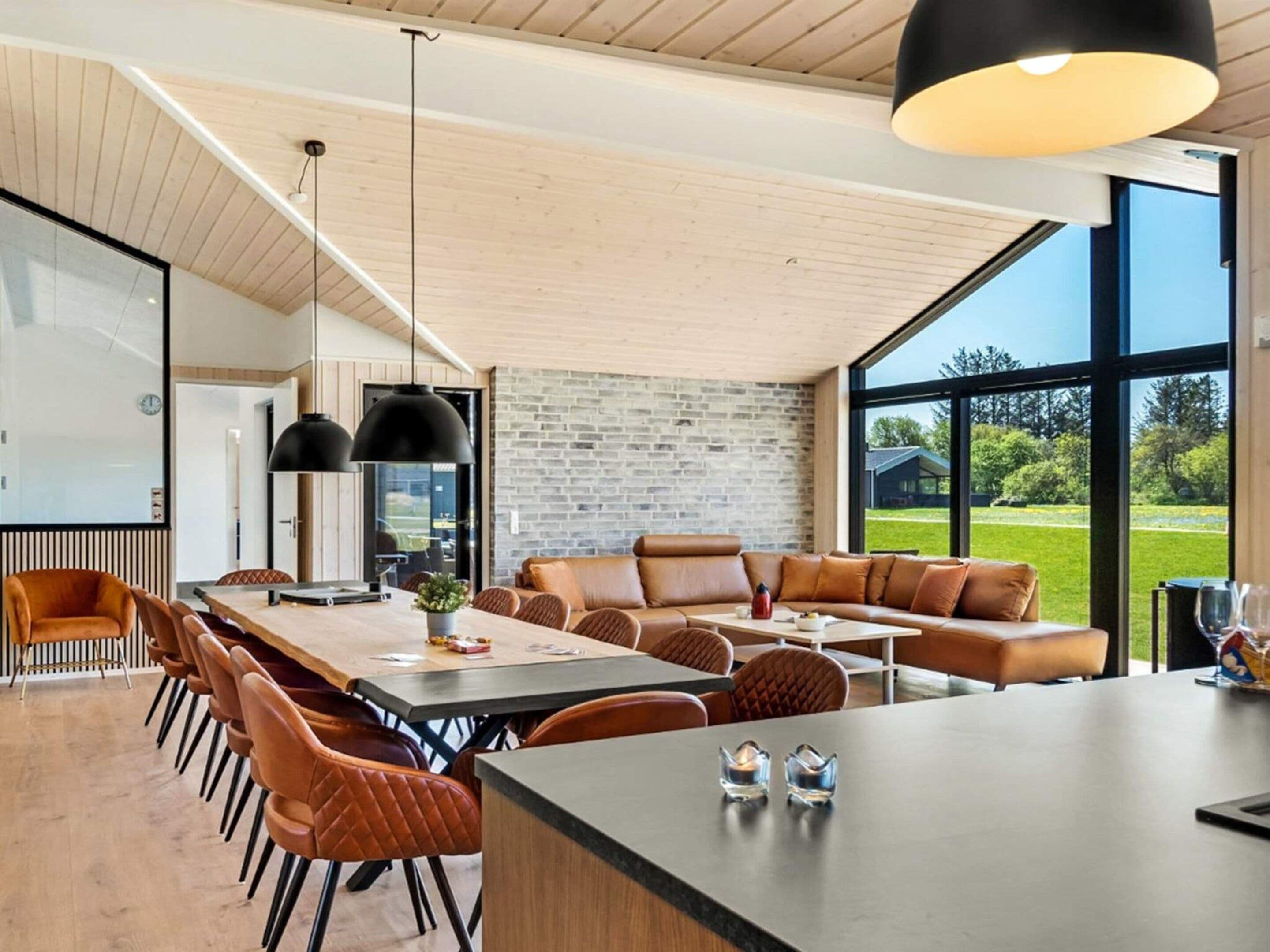 Un comedor moderno con una mesa larga, asientos de cuero y ventanas amplias que ofrecen vistas al exterior.