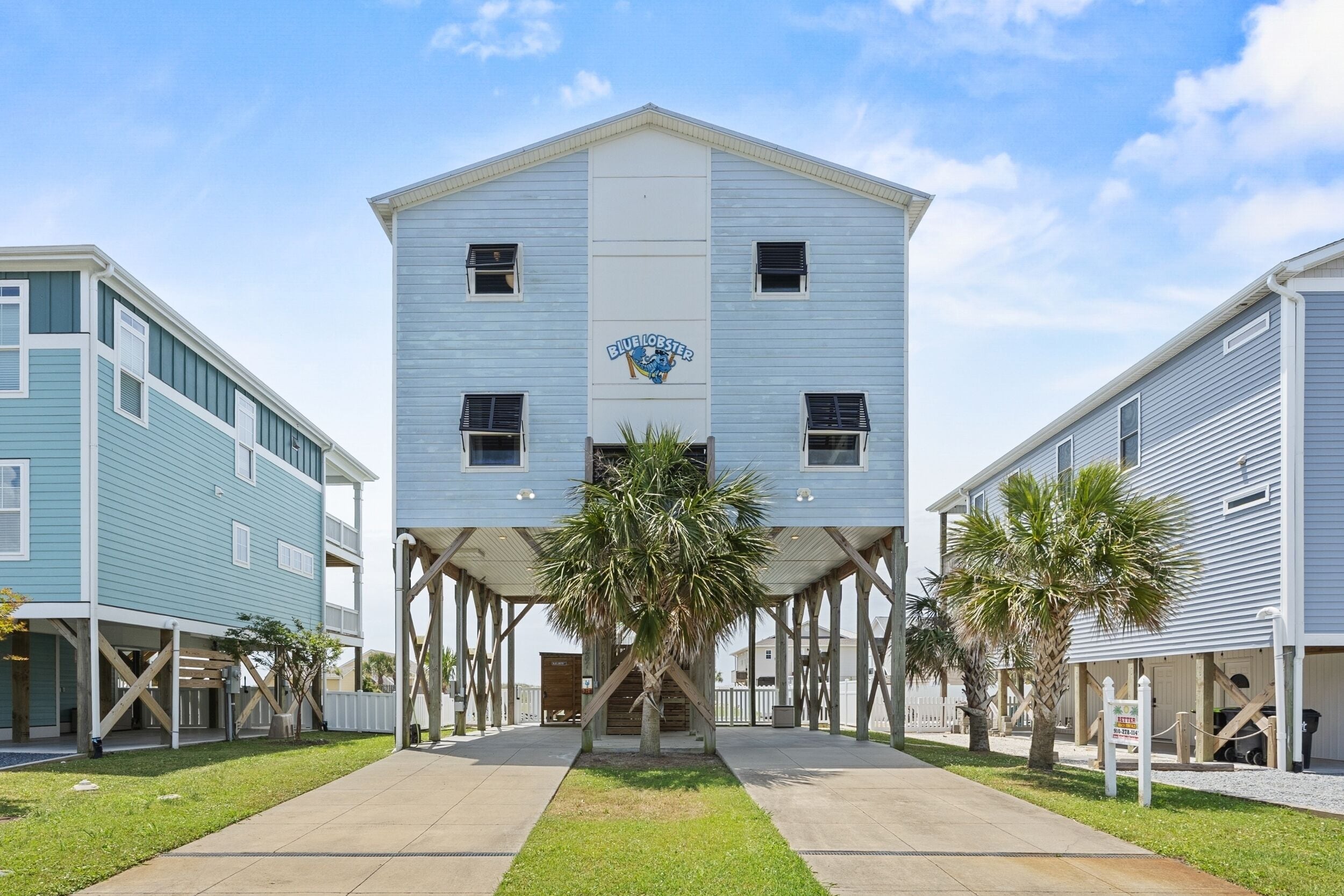 A two-story building with a central entrance, a sign above the door, and a palm tree in front.