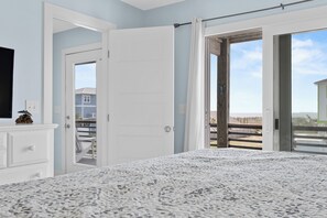 Un dormitorio con cama, cómoda y puerta que da a un balcón.