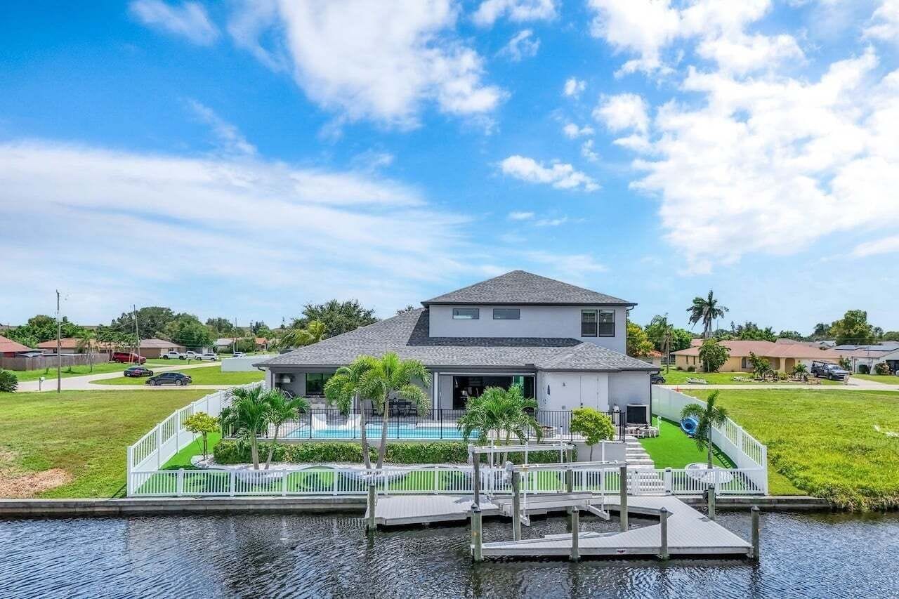 Ein zweistöckiges Haus mit Pool, Anlegesteg und umgebender Bepflanzung.