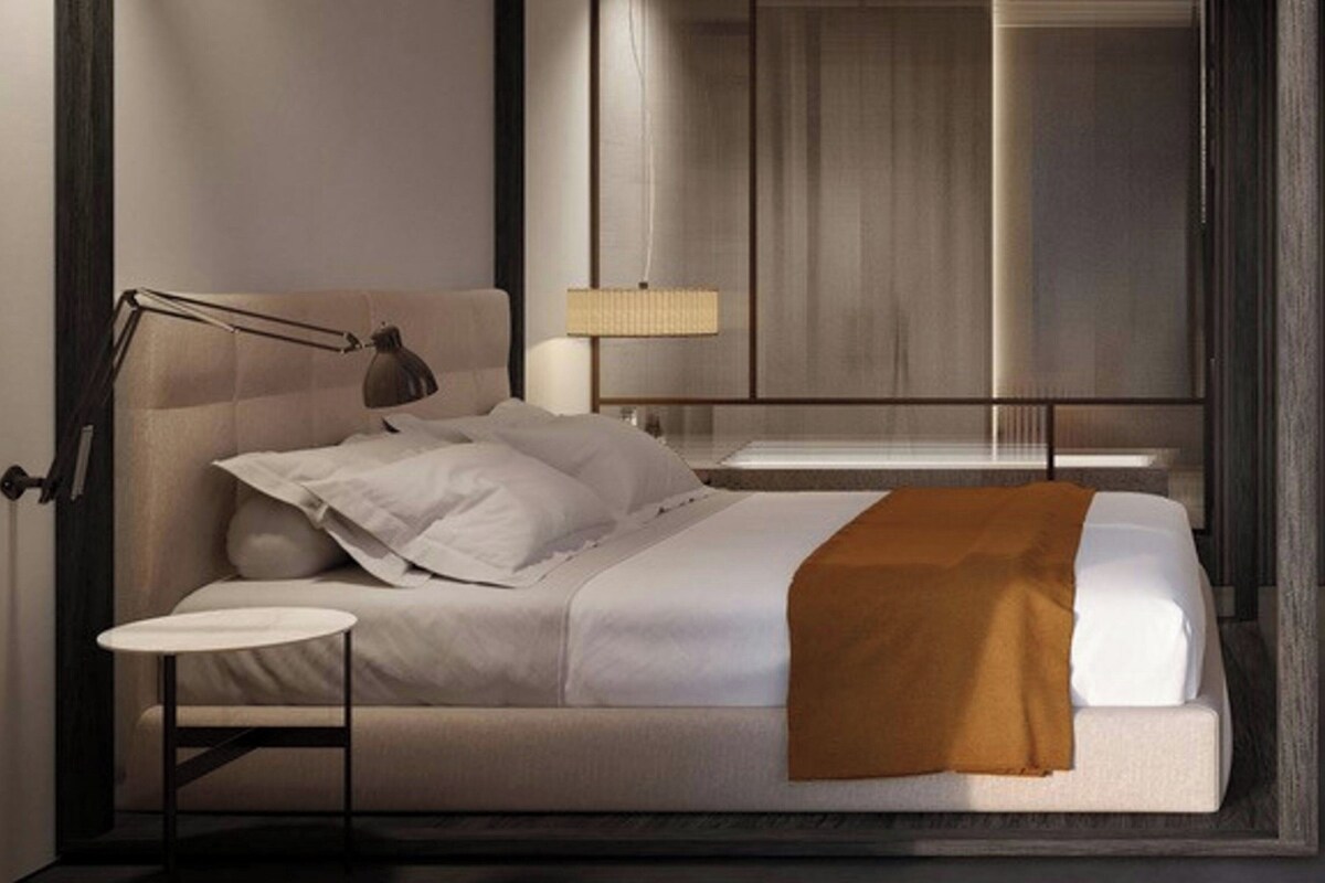 Ein modernes Schlafzimmer mit Bett, Nachttischlampe und kleinem Tisch.
